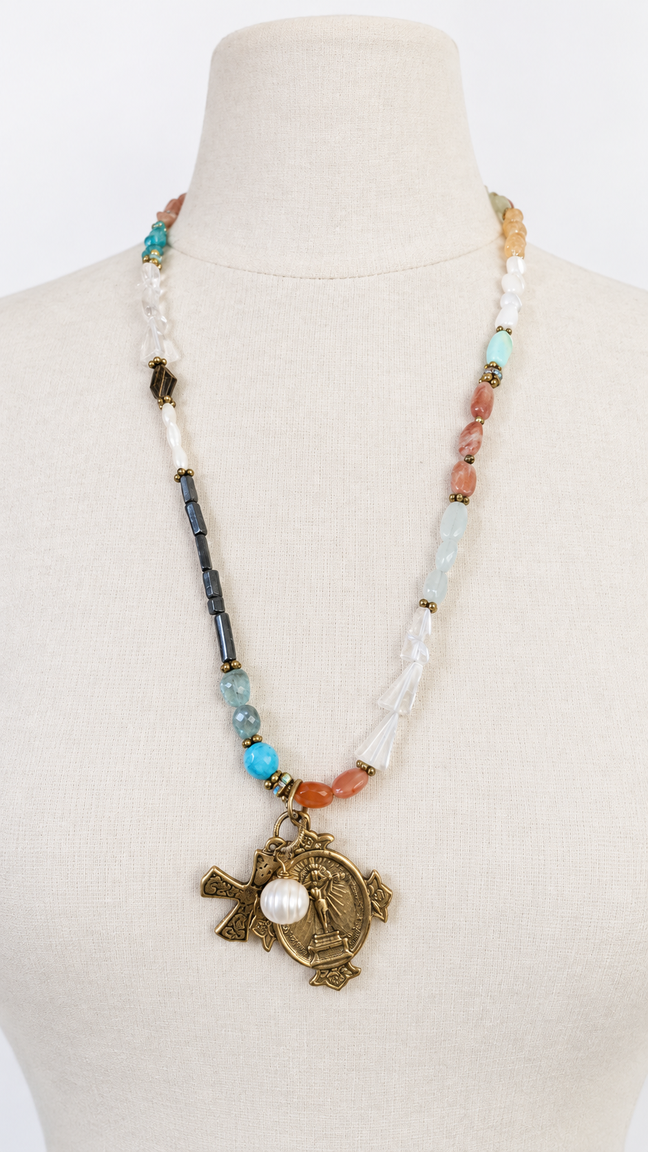 Assorted gemstone charm necklace on neutral mannequin
