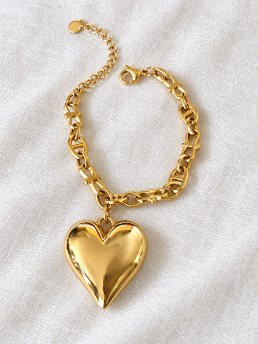Gold-plated adjustable heart charm bracelet on white linen